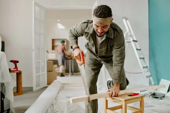 Un artisan scie du bois dans un logement neuf