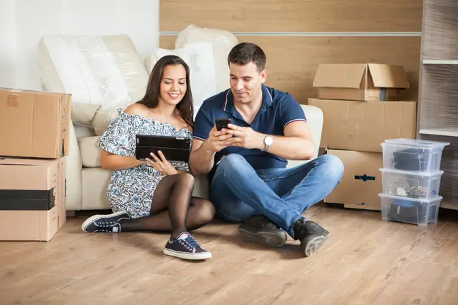 Jeune beau couple assis par terre dans leur nouvel appartement